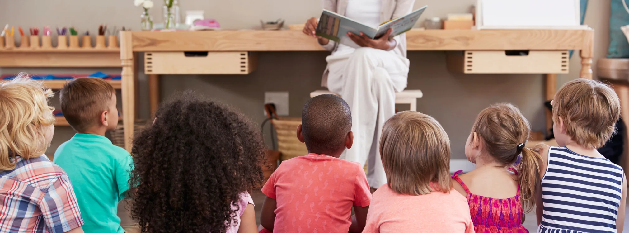 Pedagog som läser högt för en grupp barn i förskolan